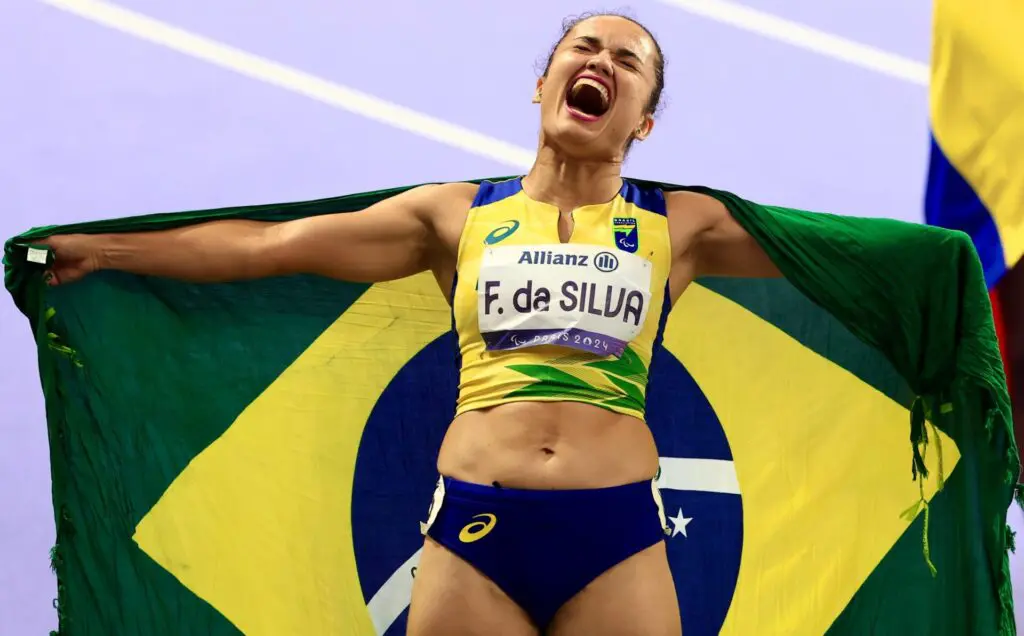 Fernanda Yara, com a bandeira do Brasil, após conquistar o ouro nos 400m, da classe T47, nos Jogos Paralímpicos Paris 2024 | Foto: Marcello Zambrana /CPB