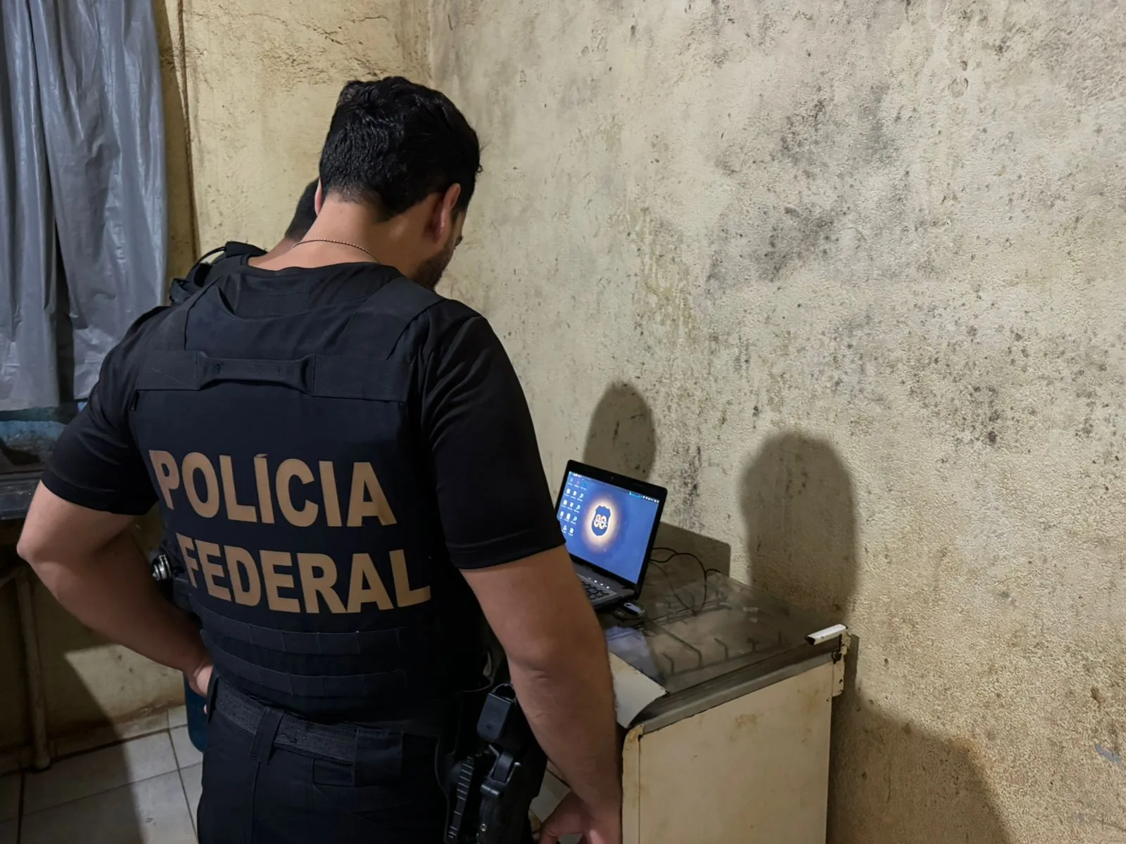 Policiais federais analisam mídias eletrônicas durante a operação que resultou na prisão de um homem por crimes de abuso sexual infantil em Marabá. 