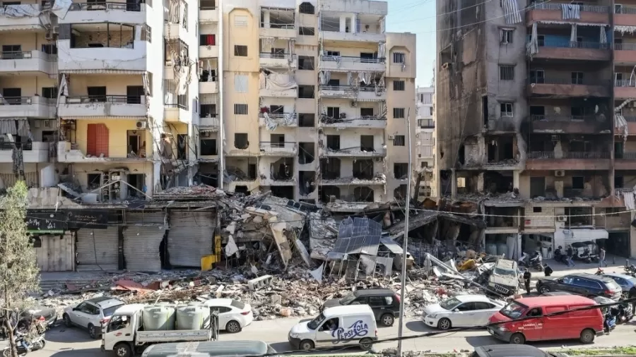 Carros passam por edifícios que foram danificados ou destruídos em ataques israelenses no bairro Hay el-Sellom, subúrbio ao sul de Beirute Imagem: ANWAR AMRO/AFP