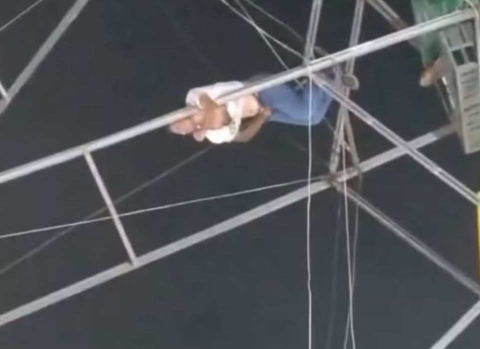 O homem conseguiu se segurar na estrutura metálica, enquanto a mulher acabou despencando. Foto: Reprodução O homem conseguiu se segurar na estrutura metálica, enquanto a mulher acabou despencando. Foto: Reprodução